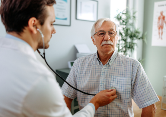 Doctor listening to older man's heartbeat