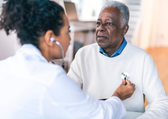 Doctor listening to older man's heartbeat