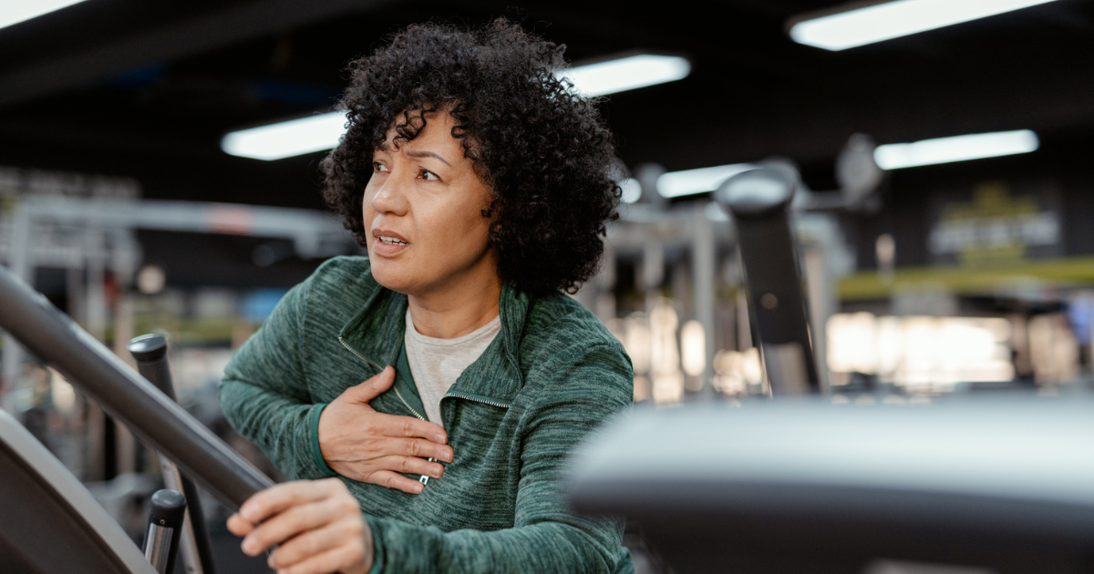 Woman on exercise machine holding chest in pain