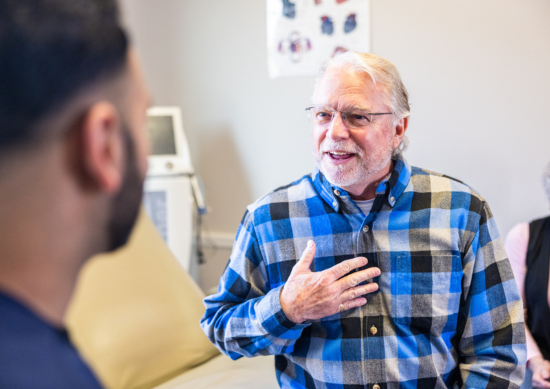 Man touching his chest and talking to doctor
