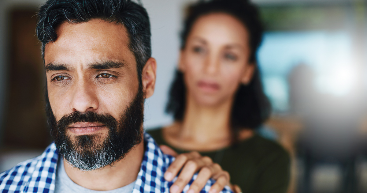 Man with woman's hand on his shoulder