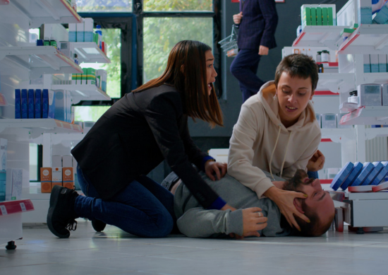 Two women helping man having a seizure