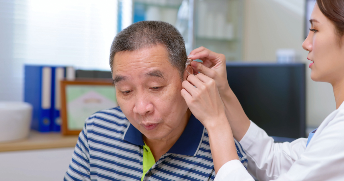 Older man getting his hearing aid adjusted by a doctor