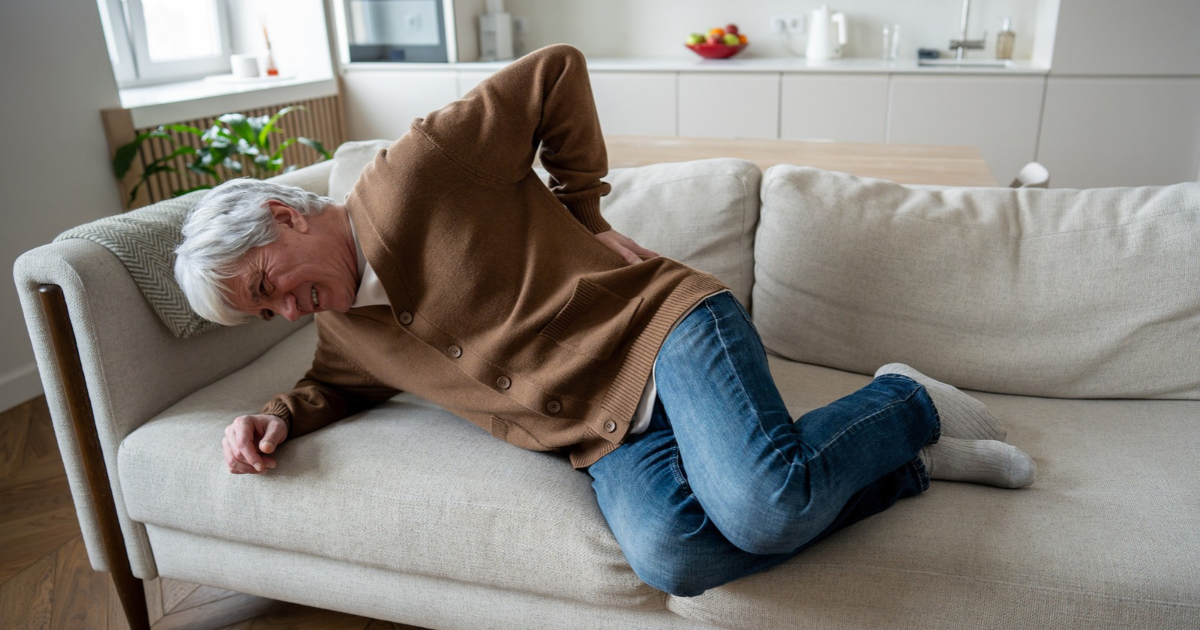 Man holding his back in pain lying on couch
