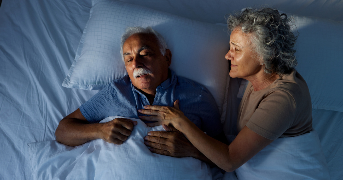 Woman in bed nudging her snoring husband