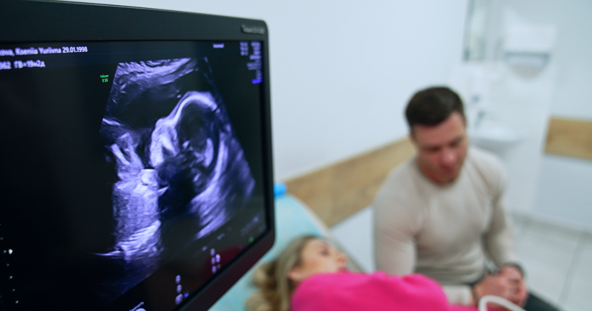 Pregnant woman receiving ultrasound with man sitting next to her