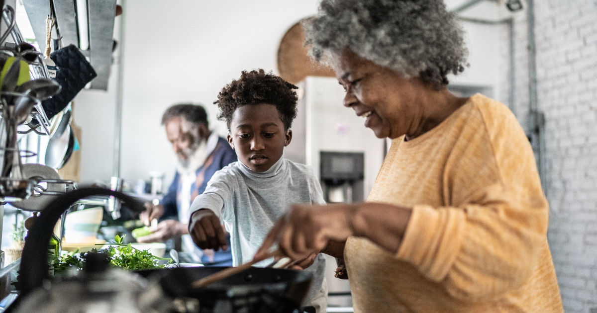 A grandmother cooking in the kitchen with her grandson