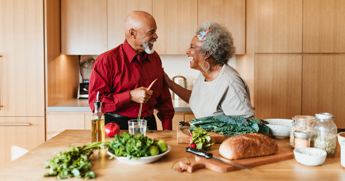 An older couple standing in the kitchen preparing a meal