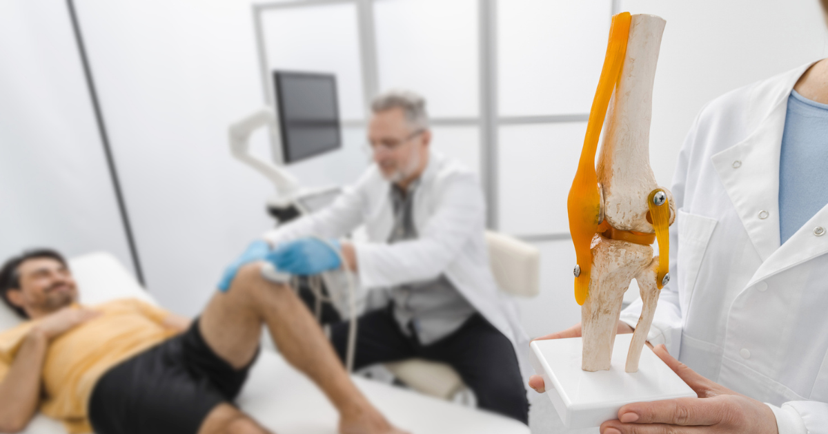 Doctor examining man's knee, doctor in foreground holding medical model of knee
