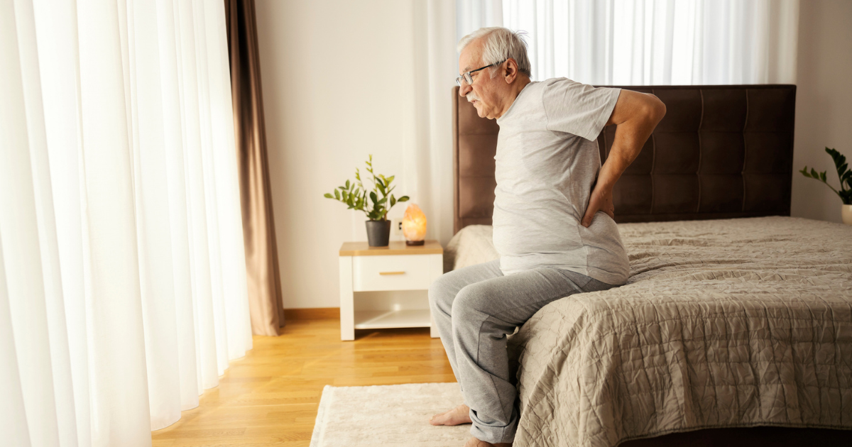Man sitting on the side of the bed with back pain