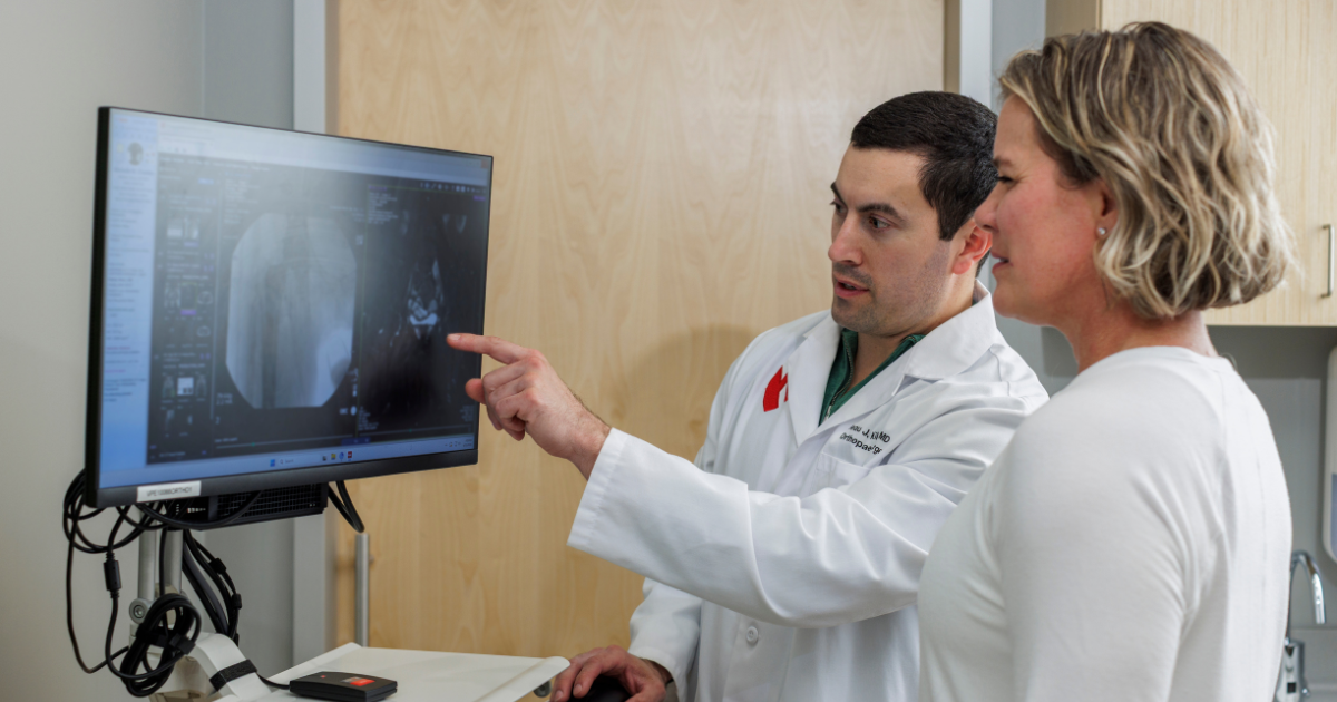 Beau Kildow, MD pointing at medical image on computer with patient Michelle Chastain