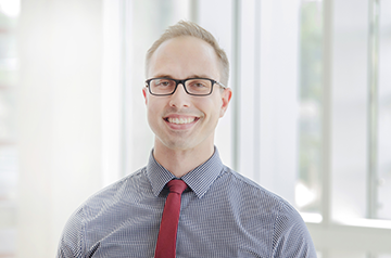 Brightly lit background and a smiling man (Logan Olson, PharmD)