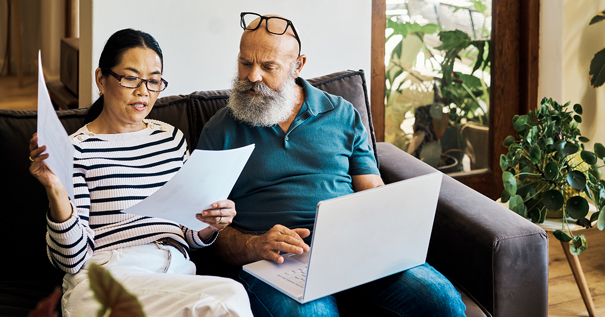 Man and woman sitting on couch looking at paperwork