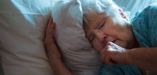 picture of an elderly woman coughing in bed