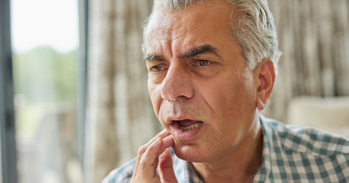 Older man holding his mouth