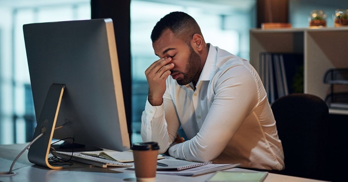 Man sitting at desk with head in hand