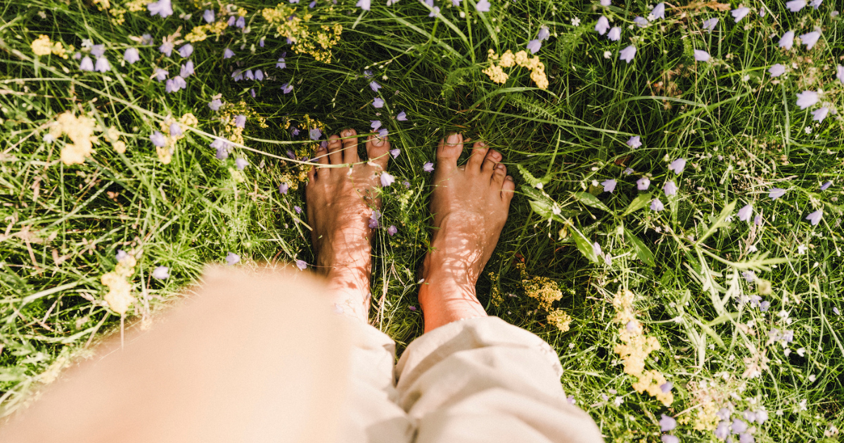 POV looking down at woman's bare feet standing in grass