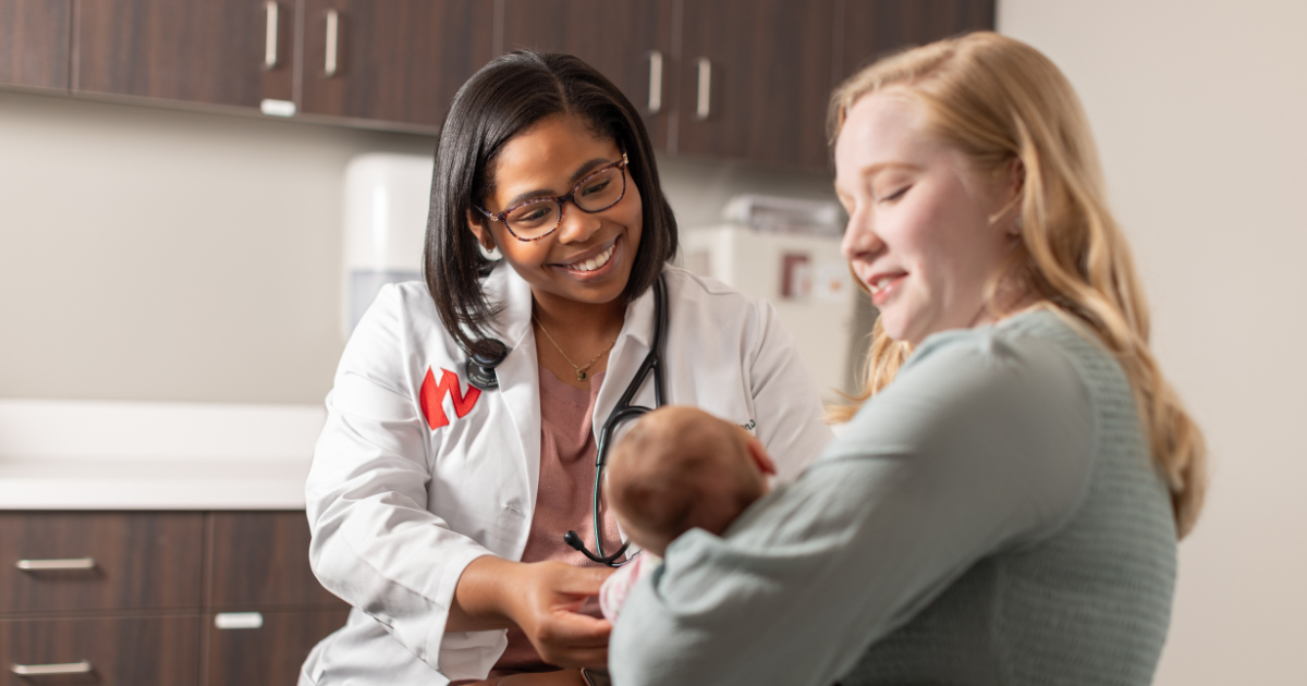 Woman holding baby talking to Nebraska Medicine doctor