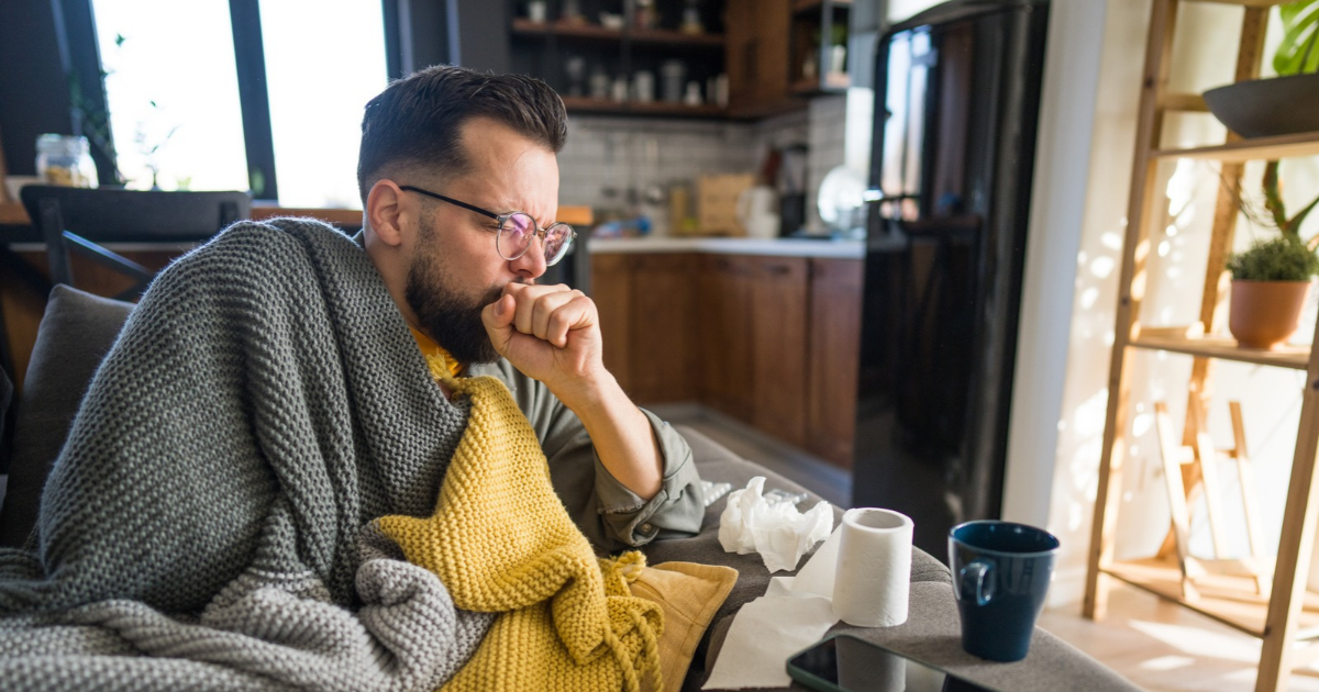 Man sitting on couch, coughing