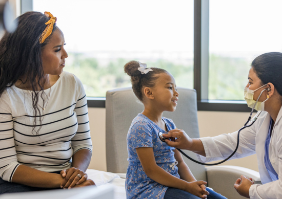 Mother and daughter in doctor's office, doctor using stethoscope