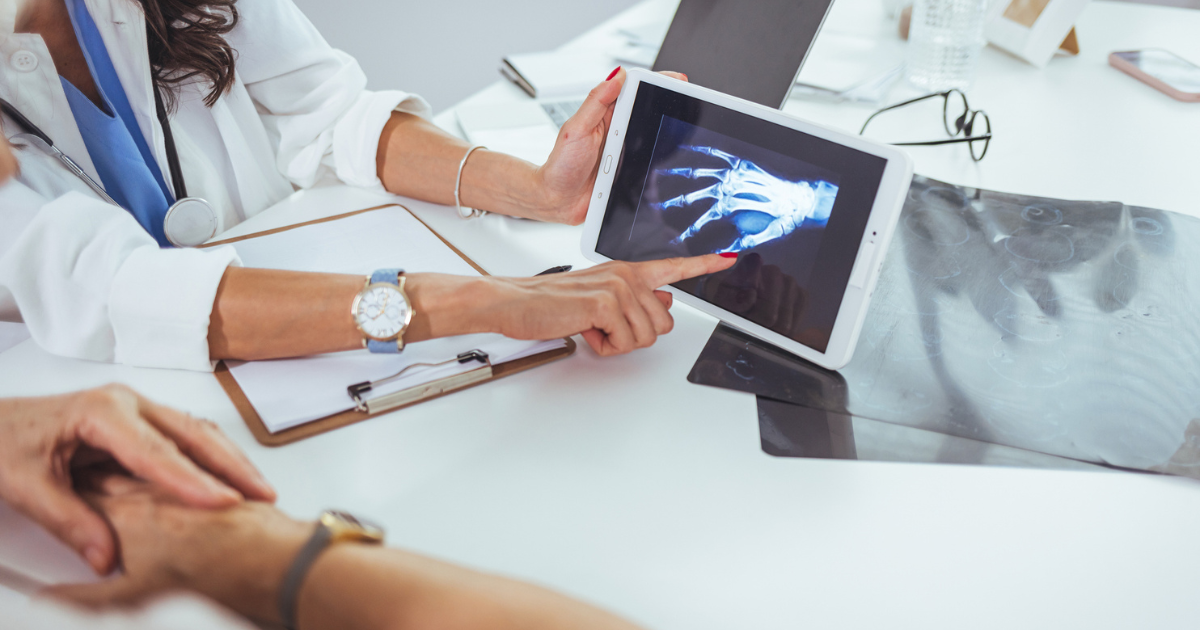 Close up of doctor showing x-ray of hand to patient