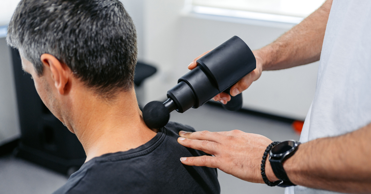 Man using massage gun on man's neck