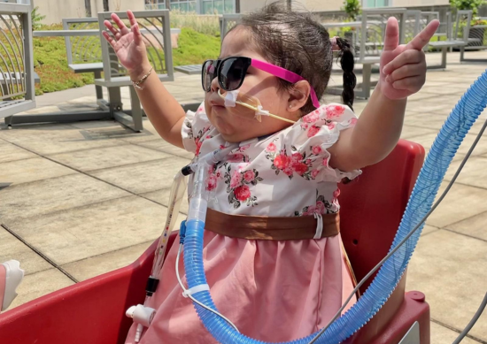 Genesis waves her hands in the air as she settles in for a wagon ride.