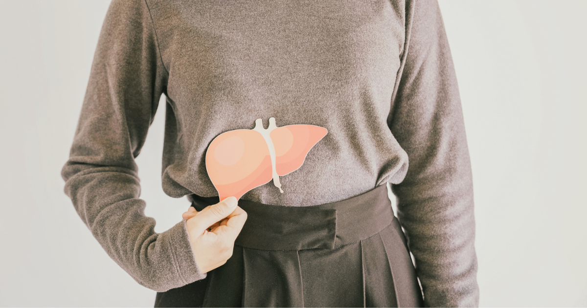 Woman holding a paper liver in front of her abdomen