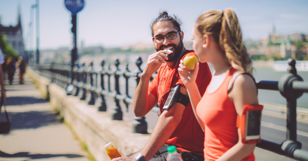 Man and woman sitting on bridge and eating
