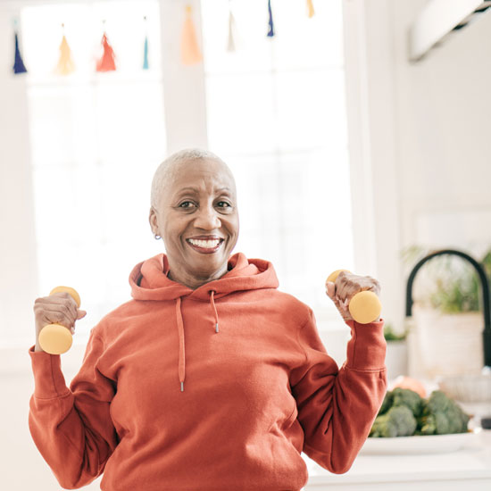 Picture of a woman lifting weights at home and smiling