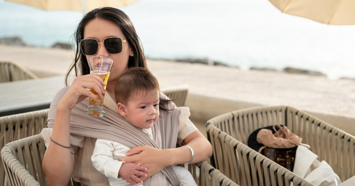 Woman sitting with baby and drinking a beer