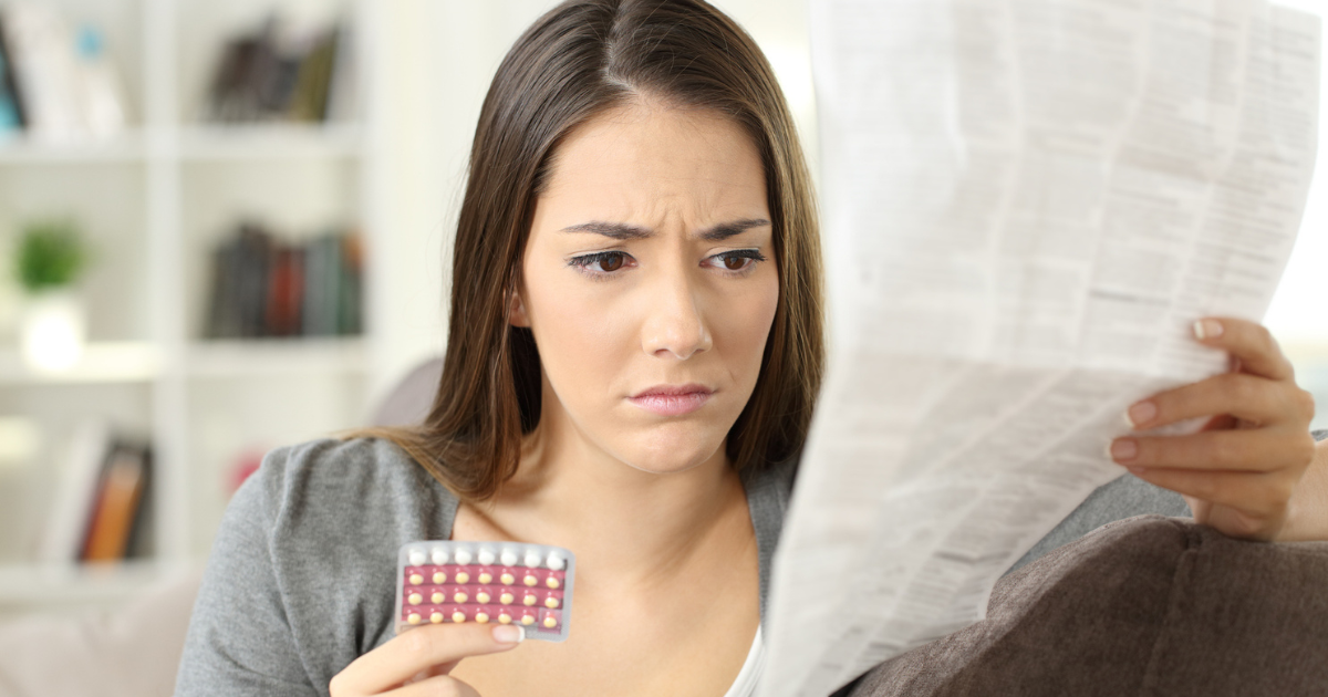 Woman looking at birth control pills