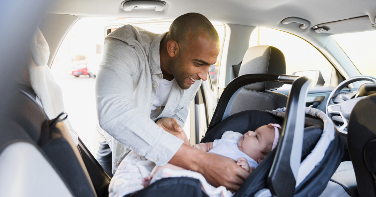 Dad putting daughter in car seat