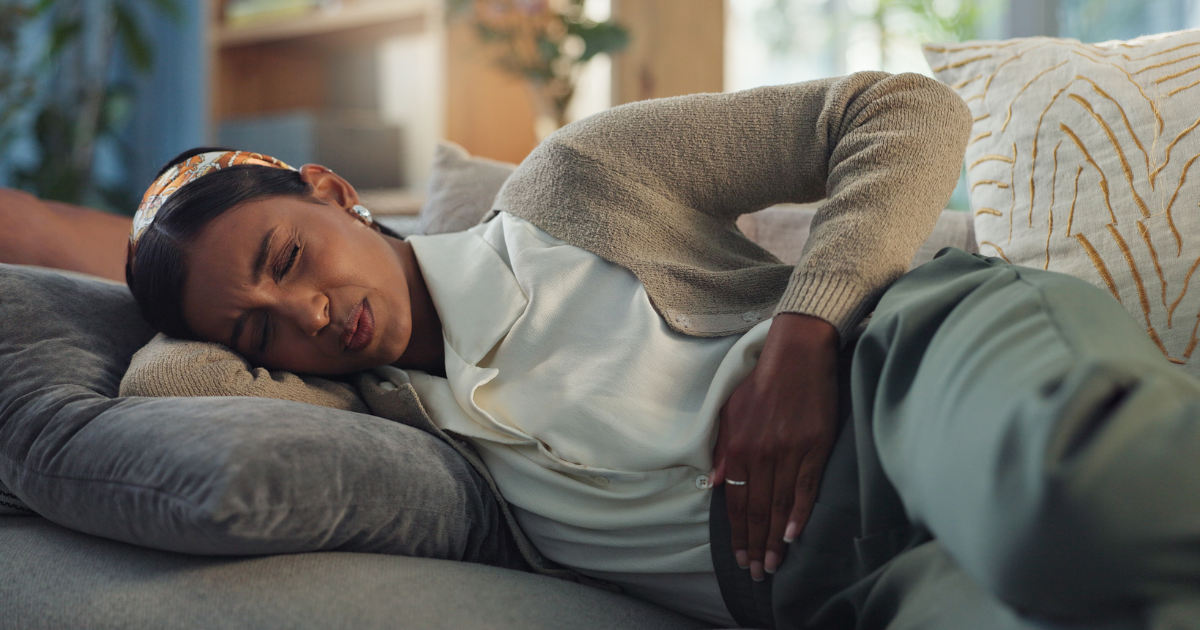 Woman lying on couch holding stomach