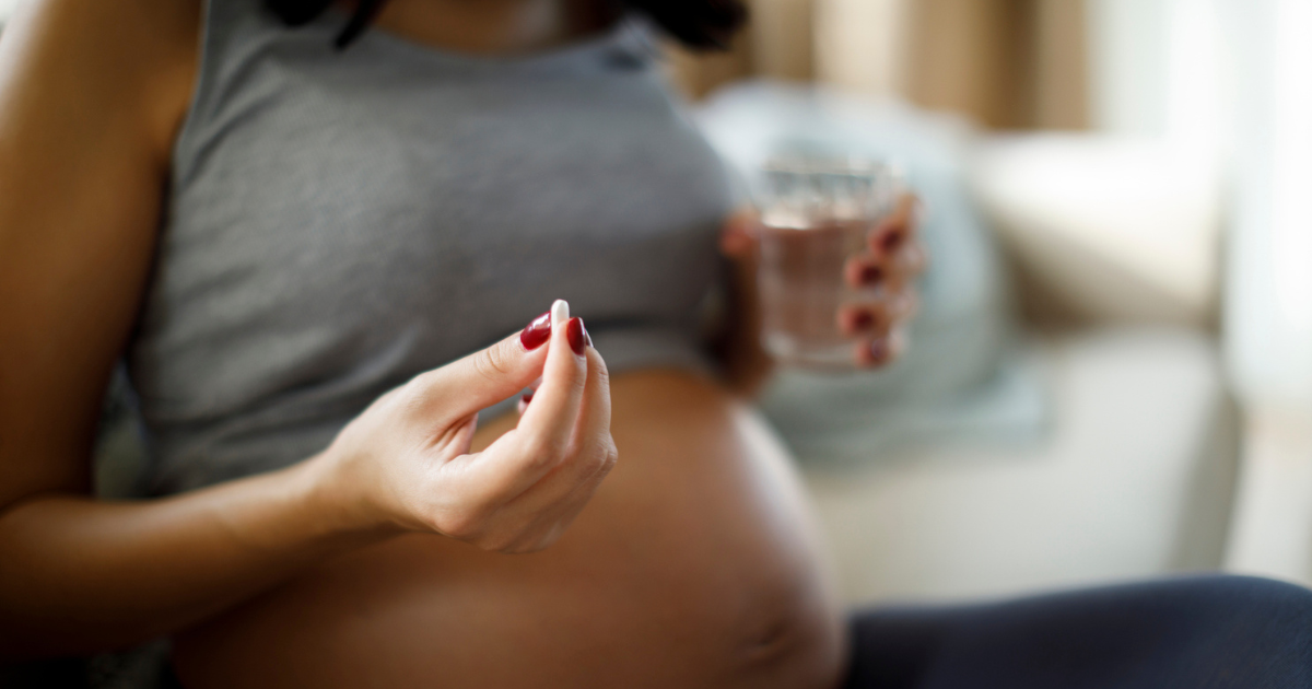 Pregnant woman holding pill