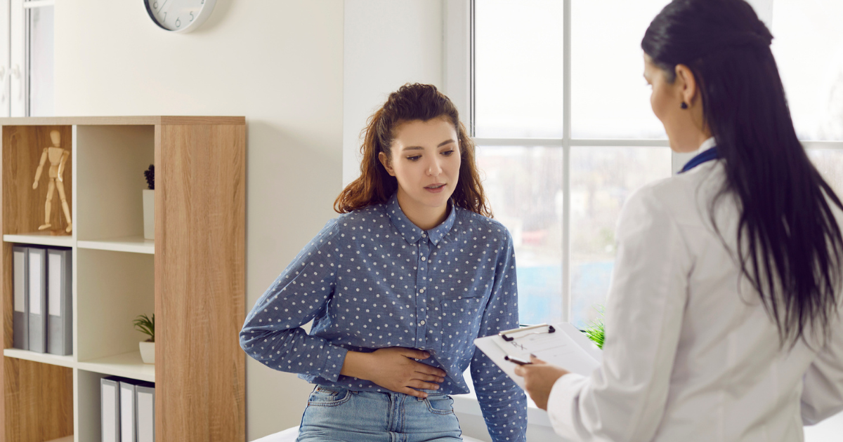 Woman holding abdomen talking to doctor
