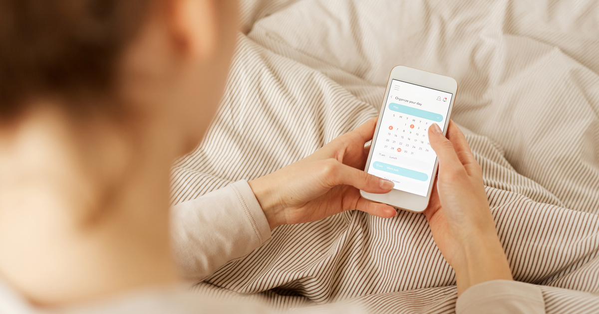 Woman holding app with calendar to track cycles