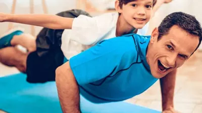 A man doing push ups with his son on his back. 
