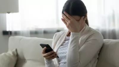 A woman covering up her face looking at her phone