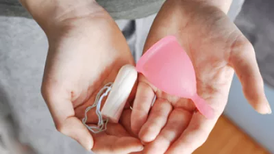 picture of a woman holding a tampon and a menstrual cup