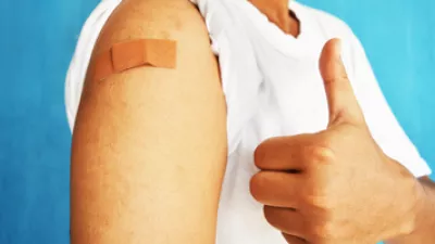 Asian man with a bandage on the arm holding up a thumbs up