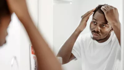 picture of a man looking at his hair in the mirror