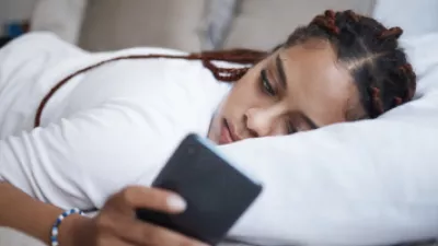 Woman laying on her bed, looking at her phone