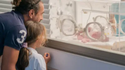 Dad and daughter looking at baby sibling in incubator