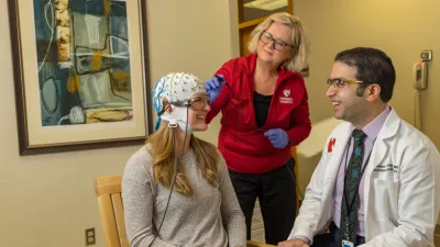 Woman with MEG mapping cap on talking to doctor with nurse in background