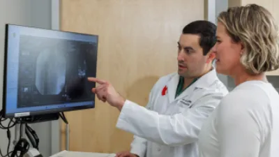 Beau Kildow, MD pointing at medical image on computer with patient Michelle Chastain