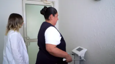 A female nutritionist giving the scale inbody handle to an overweight latina woman during a consultation.