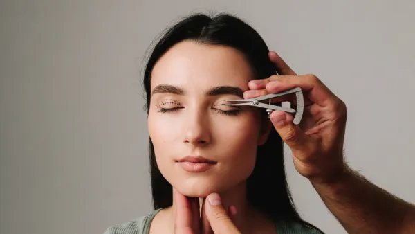 Surgeon measuring distance on woman's eyelid for blepharoplasty