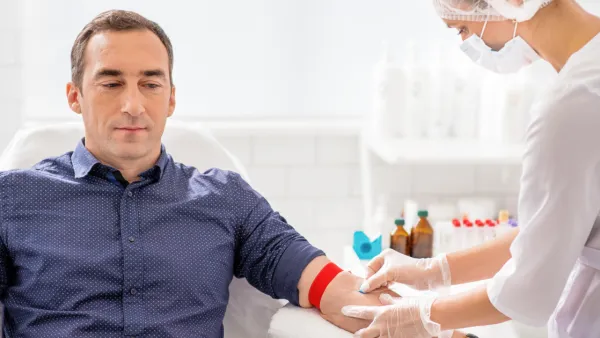 Nurse taking blood sample from man's arm