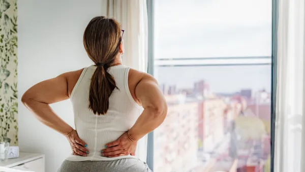 Woman sitting in bed with back pain